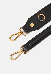 Sort læderrem med guldhardware, to karabinlåse og en glat overflade. Indeholder metalnitter og ringdetaljer til fastgørelse.