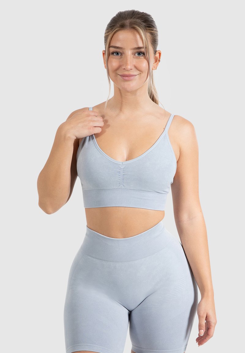 Bralette deportivo de color azul claro con tirantes finos ajustables, banda inferior acanalada y un acabado suave y texturizado, combinado con pantalones cortos de tiro alto a juego.