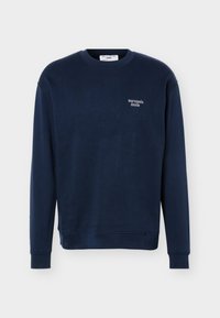 Μπλούζα μπλε ναυτικού, με στρογγυλή λαιμόκοψη, μακριά μανίκια και μικρό λογότυπο "marcopolo denim" στο αριστερό στήθος.