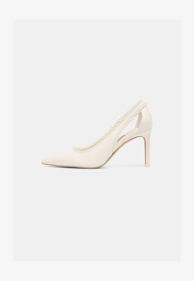 Biela lodička s ostrou špičkou na vysokom podpätku, zdobená perlami pozdĺž okrajov a s výrezom v blízkosti päty.