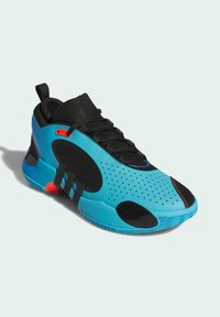 Chaussure de sport avec un design bleu et noir, tige en mesh, texture perforée, accents rouges, et semelle en caoutchouc avec motifs de traction.