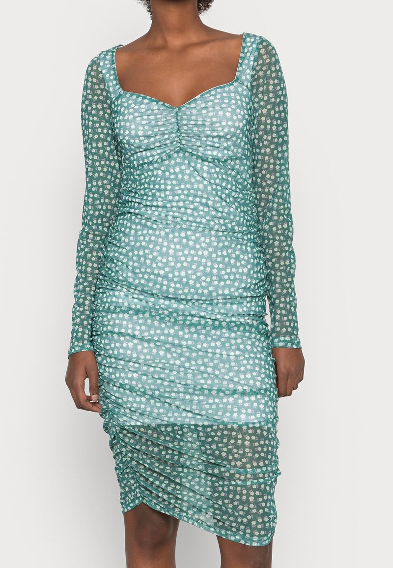 Robe en teal à manches longues avec une silhouette ajustée, présentant un design froncé et un motif floral avec de subtils accents blancs.