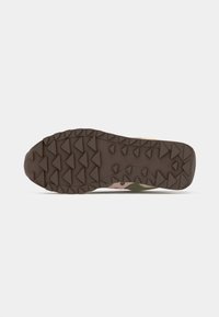 Brown rubber sneaker sole with angular grip pattern, featuring a camo design in green and tan colors, showing texture and tread detail.