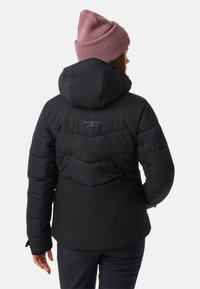 Zwarte pufferjack met een chevronpatroon op de achterkant, voorzien van een capuchon en een geribbelde mauve muts. Het materiaal lijkt glad en geïsoleerd.
