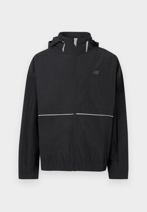 Must kerge tõmblukuga jope kapuutsiga, elastse äärega, peegeldavate triipudega rinnal ja kapuutsil ning tagasihoidliku New Balance'i logoga vasakul rinnal.