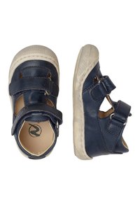 Marinblå läderskor för barn med två justerbara remmar, vita gummisulor och utskärningar på sidorna. Texturerad sula för bra grepp.