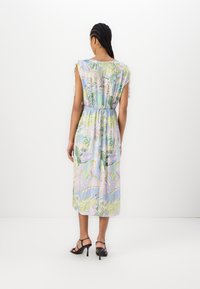Blomsterprøvd, pastelldress med korte ermer, elastisk midje og lengde til midt på leggen, laget av lett stoff. Svarte, strappy hæler.
