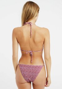 Bikini-set met een halternek en rugstrik, voorzien van een rood en paarse meerkleurige textuurpatroon en een lage scrunch broek.