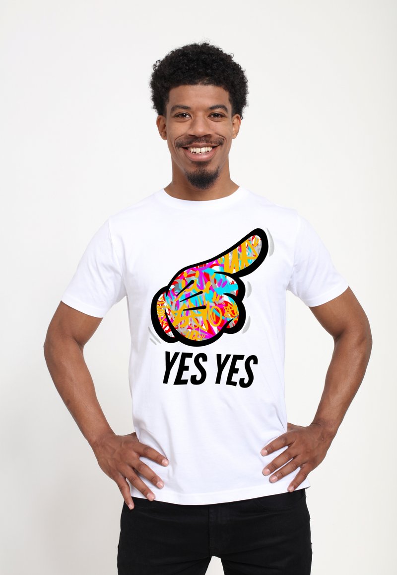 Hvid t-shirt med et farverigt grafisk motiv af en pegende hånd og teksten "JA JA" i fede sorte bogstaver.