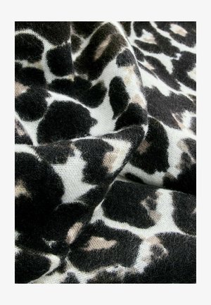 Tessuto animalier nero e beige con una texture morbida e pelosa, caratterizzato da macchie irregolari su uno sfondo bianco.