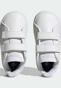 Białe sneakersy wykonane z syntetycznej skóry z siateczkowymi językami i rzepami. Okrągły nosek, wyściełany kołnierz oraz teksturowane podeszwy.
