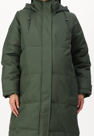 Lang olivengrøn polstret vinterjakke med hætte og snore til at stramme, båret af en person med hænder synlige ved siden.