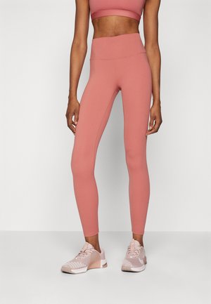 Leggings de color rosa claro con una cintura alta y textura suave, combinados con zapatillas deportivas rosa claro con detalles de malla y sólidos.