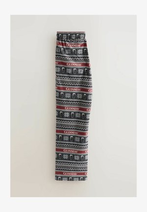Pantaloni neri con un motivo ripetuto di boccali di birra bianchi, fiocchi di neve e strisce rosse con il testo "GUINNESS" in un design festivo.