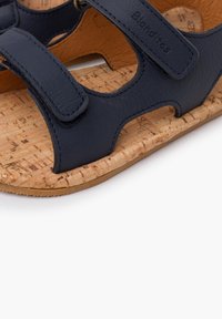 Sandali in pelle blu navy con suola in sughero, dotati di due cinturini regolabili e design con ritagli. Finitura testurizzata sulla pelle e sulla suola.