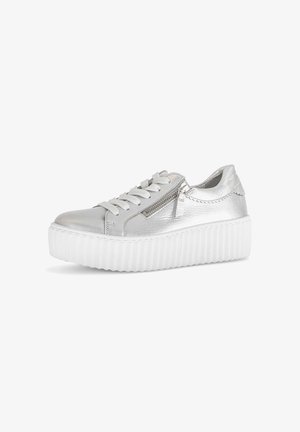 Silberner Sneaker mit niedrigem Schaft, weißer dicker profilierter Plateau-Sohle, Seitenreißverschluss und weißen Schnürsenkeln auf weißem Hintergrund.