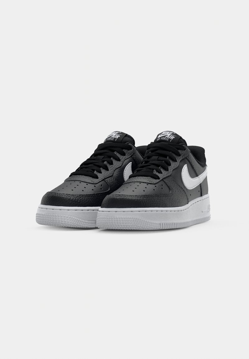 Schwarze Leder-Sneaker mit strukturiertem Finish, ausgestattet mit einem weißen Nike-Swoosh, schwarzen Schnürsenkeln und einer grauen Gummisohle. Perforiertes Zehendesign.