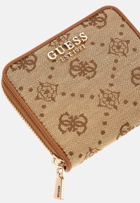 Brown canvas wallet with gold hardware, featuring a patterned design and central logo, framed by a tan zipper and trim.