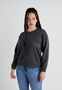 Mørkegrå hettegenser med lange ermer, rund hals og ribbede mansjetter; kombinert med blå jeans. Glatt tekstur, avslappet passform og minimalistisk design.