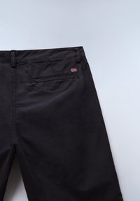 Pantalon noir avec une poche arrière comportant une petite écusson du drapeau norvégien sur le côté supérieur droit de la ceinture.