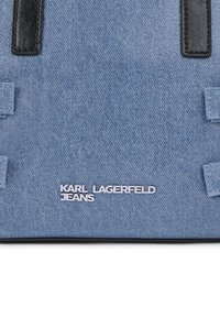 Τσάντα από τζιν σε ανοιχτό μπλε χρώμα με μαύρες δερμάτινες λεπτομέρειες και ραφές, φέρει το λογότυπο "KARL LAGERFELD JEANS" σε λευκό χρώμα. Ορθογώνιο σχήμα.