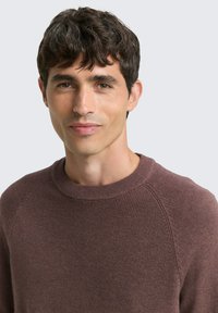 Bruine ronde hals trui met geribbelde textuur en raglanmouwen, gemaakt van zacht materiaal. Heldere stitching en een eenvoudig ontwerp.