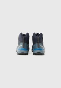 Botas de caminhada azuis e cinzentas com um design de cano alto, parte superior texturizada, calcanhar reforçado e um sistema de atacadores proeminente. Solado de borracha anti-derrapante visível.