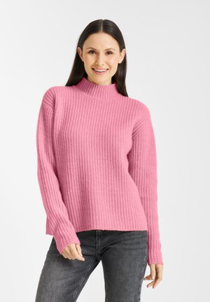 Roze ribgebreide trui met een hoge kraag, lange mouwen en een relaxte pasvorm, gecombineerd met donkergrijze jeans. Getextureerde stof met zijsplitten.
