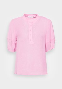 Blusa rosa de manga curta com gola mandarim, apresentando uma lista de botões e pequenas bolinhas brancas num tecido leve e texturizado.