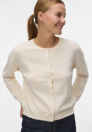 Cardigan color beige chiaro realizzato in materiale morbido, con scollo rotondo, maniche lunghe e una chiusura frontale con bottoni semplici.