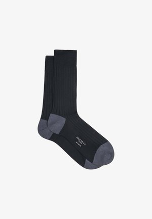 Calcetines negros acanalados con contraste en el talón y la puntera de color gris oscuro. Elaborados con un material suave que presenta un logo cerca del área del tobillo.
