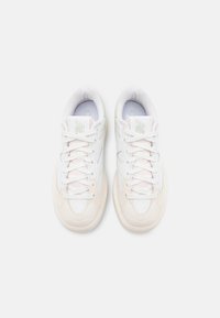 Vita lågskor med ljusbeiga accenter och snören, sedd uppifrån på en enfärgad vit bakgrund.