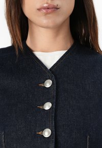 Donker denim gilet met vier zilveren knopen, een V-halslijn en zichtbare stiksels. Soepele textuur met een klassiek ontwerp.