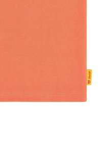 Tessuto color corallo arancione con una trama texture; presenta un'etichetta gialla con un logo di orso nell'angolo in basso a destra; forma rettangolare.