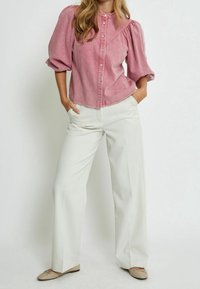 Rosa denimskjorta med knappar och volangärmar, parat med vita vida byxor och beige ballerinas.