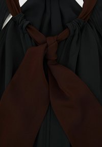 Nudo de tela bicolor con tela marrón oscura y negra, atado en un nudo decorativo y suelto sobre un fondo de tela negra.