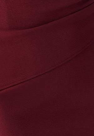 Bordeaux gekleed stof met een licht gekreukt oppervlak, voorzien van een diagonale naaddetails over het midden.