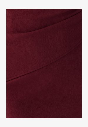 Bordeaux gekleed stof met een licht gekreukt oppervlak, voorzien van een diagonale naaddetails over het midden.