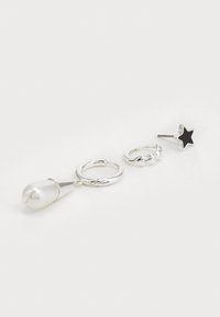 Ensemble de boucles d'oreilles en argent comprenant une pendante en perle, un anneau tordu et une étoile clou. La perle a la forme d'une goutte d'eau, l'étoile est noire.
