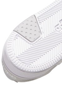 Semelle de chaussure blanche avec motif en chevrons et patch rectangulaire texturé près du talon.