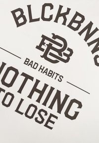 Witte stof met vetgedrukte zwarte tekst, met "BLCKBNNS," "BAD HABITS," en "NOTHING TO LOSE." Inclusief een afgerond logoontwerp.