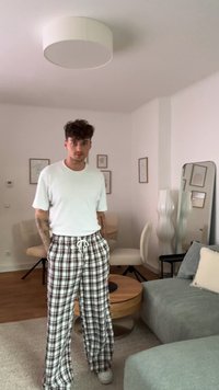 T-shirt branco de manga curta combinado com calças de pijama xadrez em cores vermelha, preta e branca. Ajuste casual e cintura com cordão.