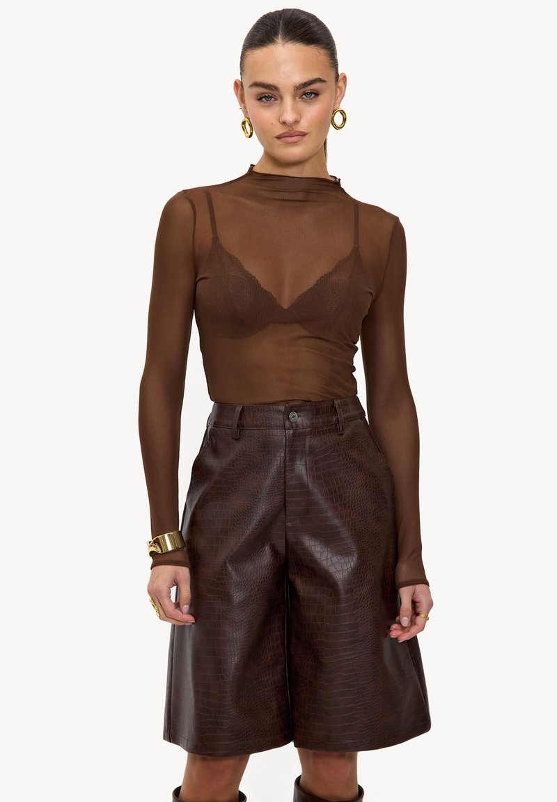 Haut long marron transparent à manches longues avec un col montant, associé à un short court en faux cuir marron à texture crocodile et poches avant.
