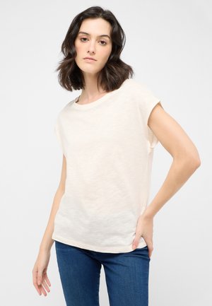 Short-sleeve cream T-shirt, lightweight fabric, relaxed fit, round neckline, subtle texture, paired with blue jeans.