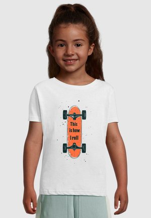 Hvit t-skjorte med et oransje skateboard-trykk og teksten "Slik ruller jeg." T-skjorten har korte ermer og rund hals.