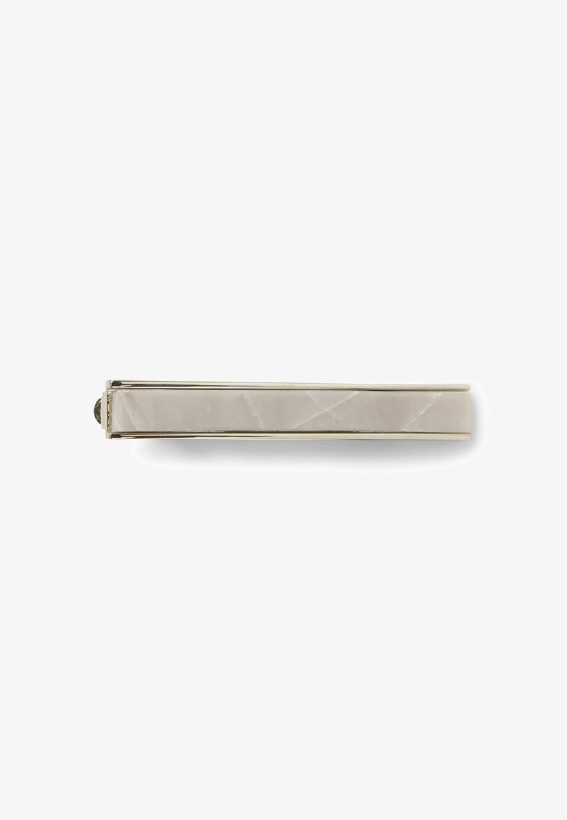 Metal hair clip with a sleek, elongated design, featuring a smooth, pale beige stone inlay and a polished metallic edge.