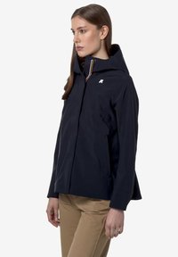 Ναυτικό μπλε αδιάβροχο μπουφάν με κουκούλα, που διαθέτει μπροστινό φερμουάρ και λογότυπο στο στήθος. Λείος υφασμάτινος σχεδιασμός και πλαϊνές τσέπες.