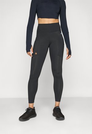 Zwarte leggings met hoge taille, twee zijzakken en een klein bruin logo. Gemaakt van rekbaar materiaal met een gladde textuur.