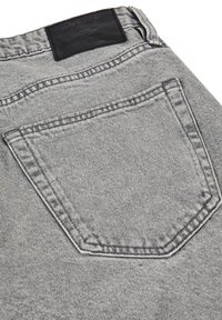 Jeans in denim grigio con tasca a toppa, cuciture gialle e un'etichetta nera del marchio sulla vita posteriore. Tessuto testurizzato con lieve usura.