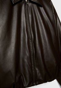 Braune Lederjacke mit glatter Textur, ausgestattet mit einem Frontreißverschluss und einem strukturierten Kragendesign. Keine sichtbaren Muster oder Akzente.